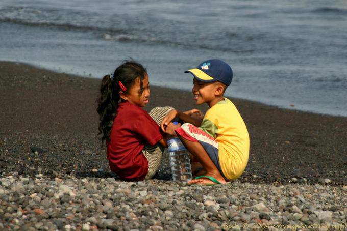 Niños de los pares que juegan en la playa, Kusamba - Bali