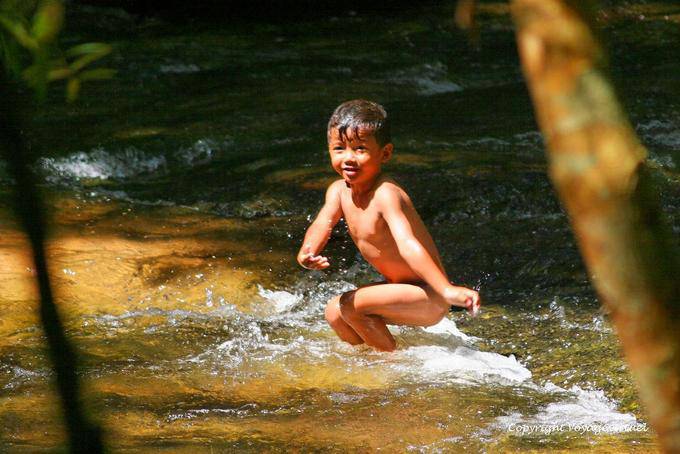 Natación del niño, el sitio web Kbal Spean, Angkor, Camboya