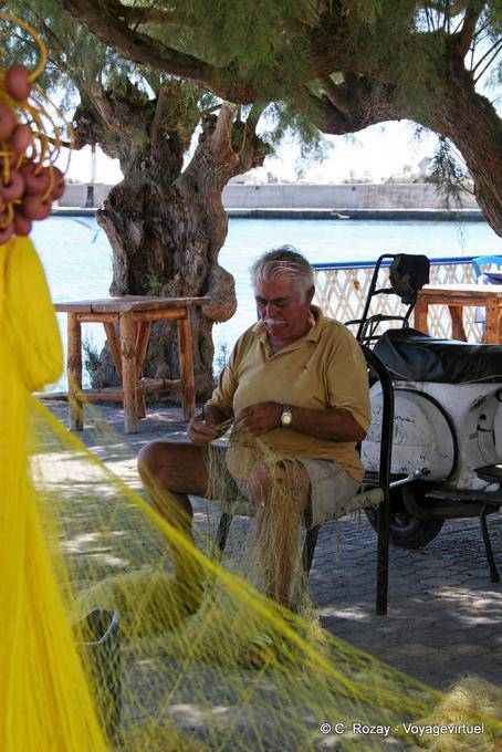Pescador sentado a lo largo del Cougioumoutzaki, Ierapetra - Creta, Grecia