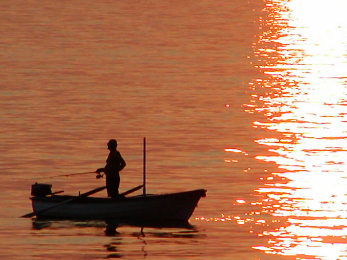 Pescador en su barco en el mar enrojecido por el sol, Starigrad, Croacia