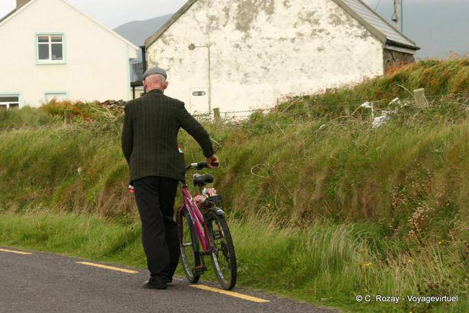 La tapa de pasar empujando su bicicleta, Dingle - Irlanda