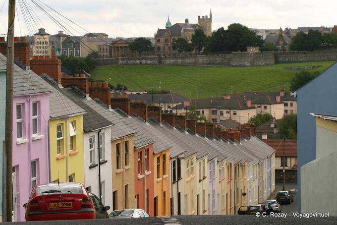 Calle empinada con fachadas de colores frente a las murallas, de Derry - Irlanda del Norte