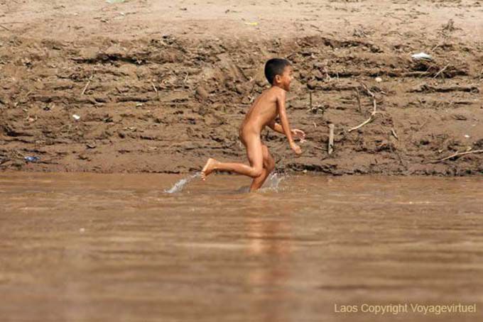 Joven Lao correr desnudo en la orilla del Mekong Laos Sud, Laos