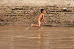 Joven Lao correr desnudo en la orilla del Mekong Laos Sud, Laos.