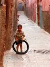Un niño que juega con un callejón de neumáticos de la Medina, Marrakech, Marruecos.