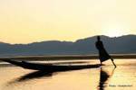 El pescador Intha remar con un remo en torno al cual serpentea pierna, Lago Inle, Birmania.
