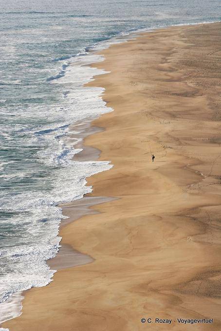 El pescador solo en la gran playa al norte de Nazaré - Portugal