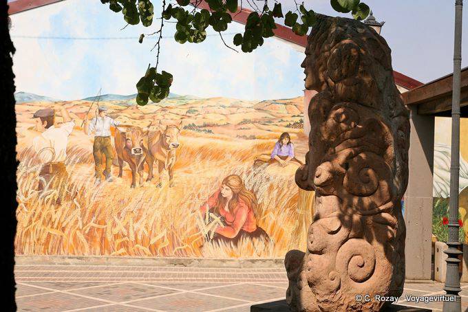 Tinnura, la Piazza del Municipio, la estatua en frente del escenario de la cosecha - Cerdena