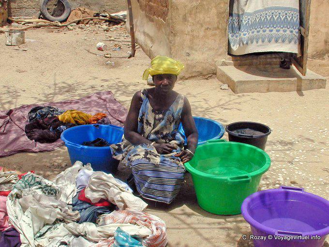 Mujer en cuclillas en medio de cubos multicolores lavandería - Senegal
